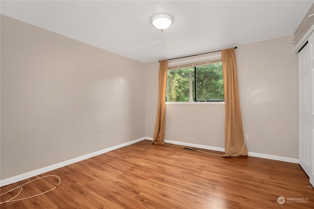 spare room featuring baseboards and light wood finished floors