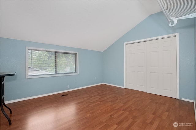 unfurnished bedroom with visible vents, baseboards, a closet, wood finished floors, and vaulted ceiling