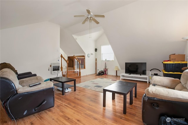 living area featuring stairway, light wood finished floors, a ceiling fan, and heating unit