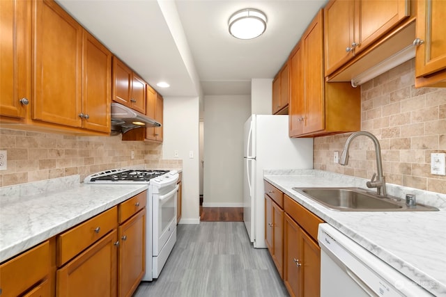 kitchen featuring light hardwood / wood-style floors, decorative backsplash, white appliances, and sink