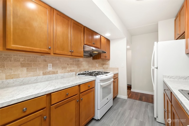 kitchen with white appliances, light stone countertops, light hardwood / wood-style flooring, and tasteful backsplash