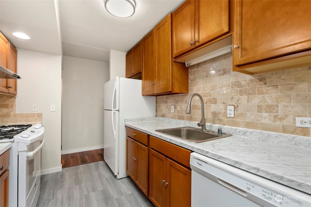 kitchen featuring backsplash, light wood-type flooring, white appliances, and sink