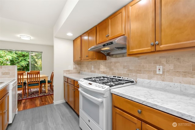 kitchen featuring light hardwood / wood-style floors, backsplash, white appliances, and light stone counters