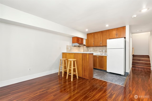 kitchen with decorative backsplash, white refrigerator, dark hardwood / wood-style floors, and sink