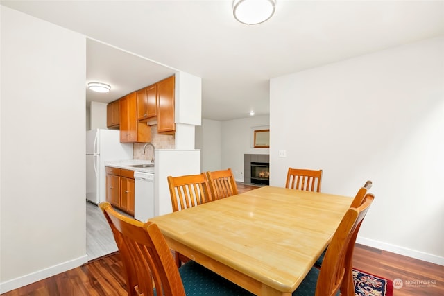 dining area featuring sink, a tiled fireplace, and hardwood / wood-style floors