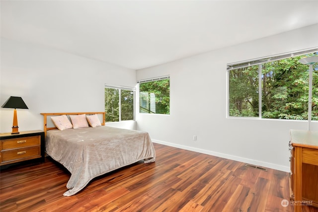 bedroom with dark wood-type flooring and multiple windows