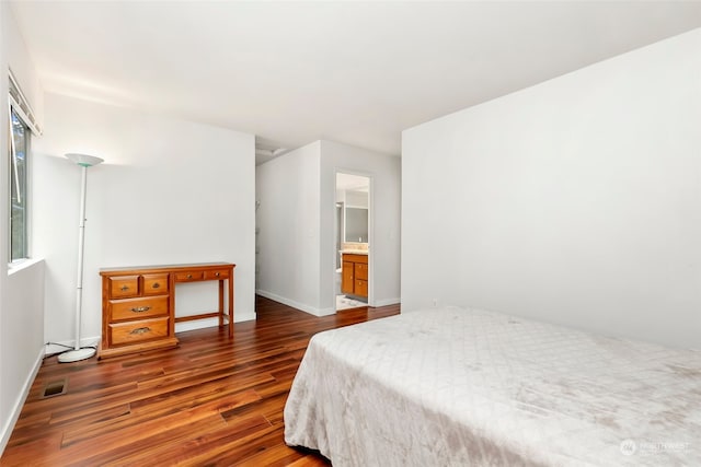 bedroom with dark hardwood / wood-style floors and ensuite bath