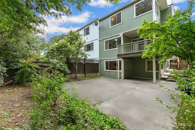 rear view of property featuring a balcony and a patio