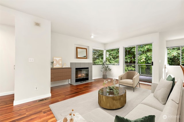 living room with wood-type flooring and a tiled fireplace