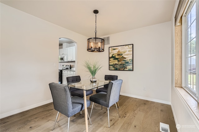 dining space with light wood-type flooring, plenty of natural light, and a chandelier