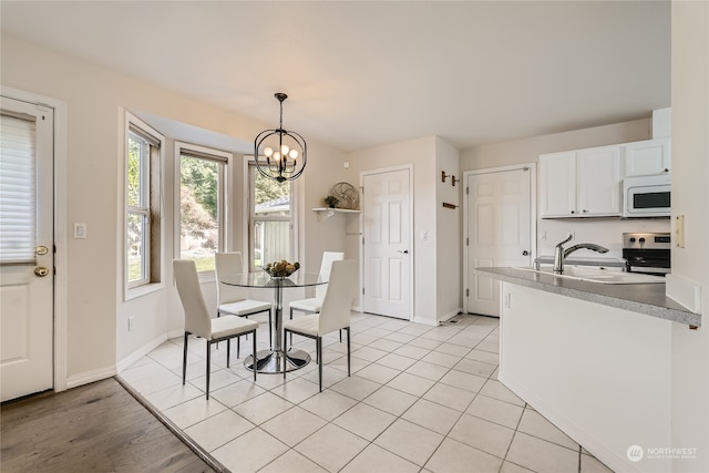 tiled dining room featuring an inviting chandelier and sink