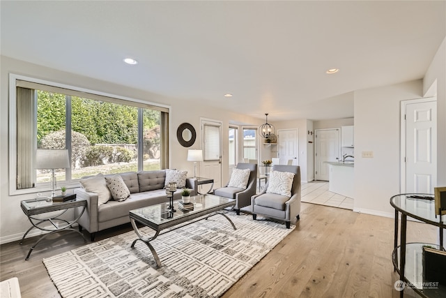 living room featuring a chandelier, light hardwood / wood-style floors, and plenty of natural light