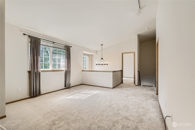 spare room featuring light carpet, an inviting chandelier, lofted ceiling, and baseboard heating