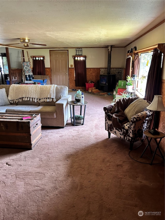 carpeted living room with a textured ceiling, ceiling fan, and a wood stove