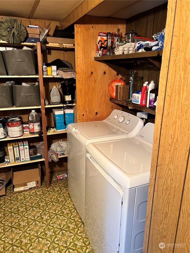 laundry area featuring wood walls and washing machine and clothes dryer