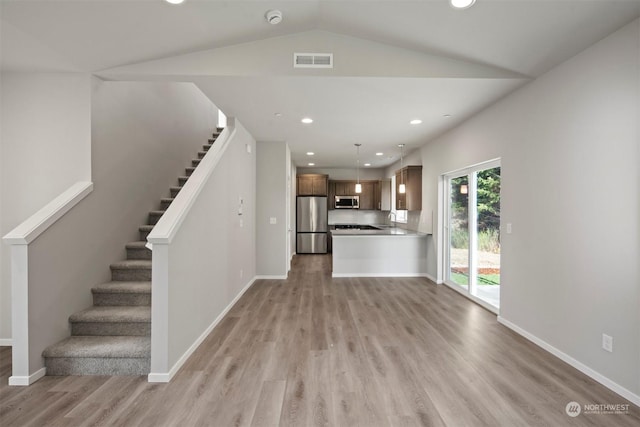 unfurnished living room featuring lofted ceiling, sink, and light hardwood / wood-style floors