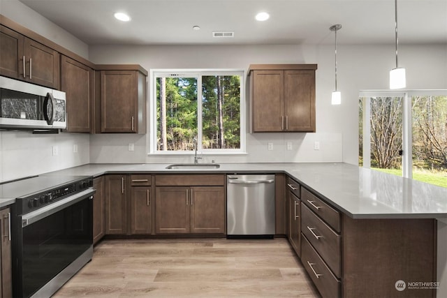 kitchen with sink, decorative light fixtures, kitchen peninsula, and appliances with stainless steel finishes