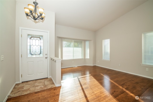 entrance foyer with lofted ceiling, hardwood / wood-style floors, and a notable chandelier