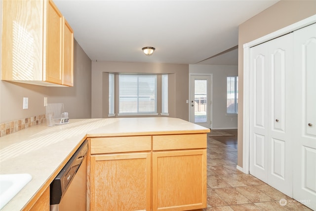 kitchen with light brown cabinets, kitchen peninsula, and stainless steel dishwasher