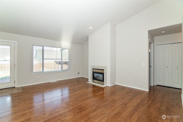 unfurnished living room featuring lofted ceiling, a tile fireplace, and hardwood / wood-style flooring