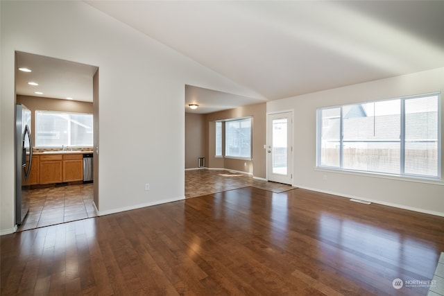 unfurnished living room with wood-type flooring, vaulted ceiling, and sink