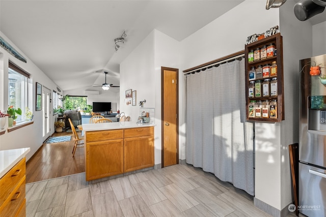 kitchen featuring light hardwood / wood-style floors, lofted ceiling, kitchen peninsula, stainless steel refrigerator with ice dispenser, and ceiling fan