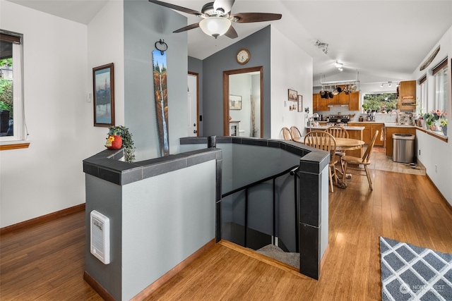 kitchen with light wood-type flooring, kitchen peninsula, vaulted ceiling, and a wealth of natural light