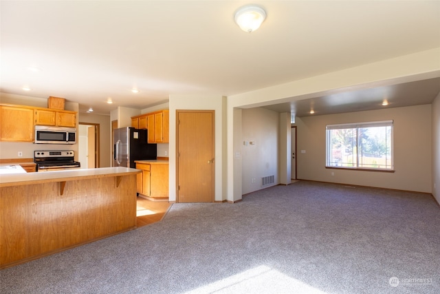 kitchen featuring kitchen peninsula, light carpet, a kitchen breakfast bar, and stainless steel appliances