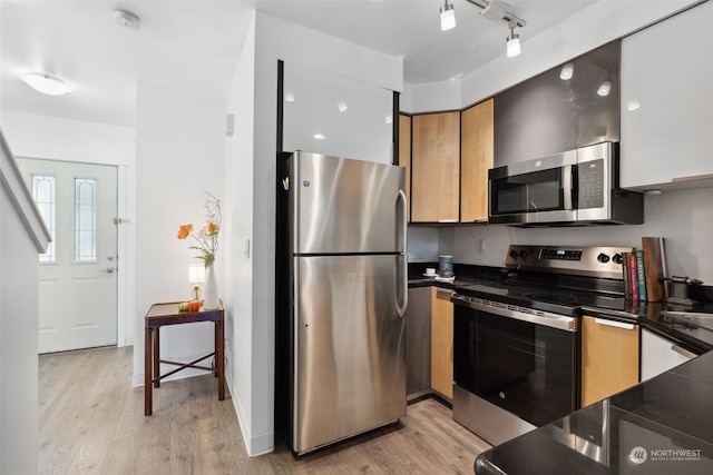 kitchen with rail lighting, appliances with stainless steel finishes, and light hardwood / wood-style flooring