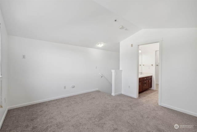 empty room featuring light carpet, vaulted ceiling, and sink