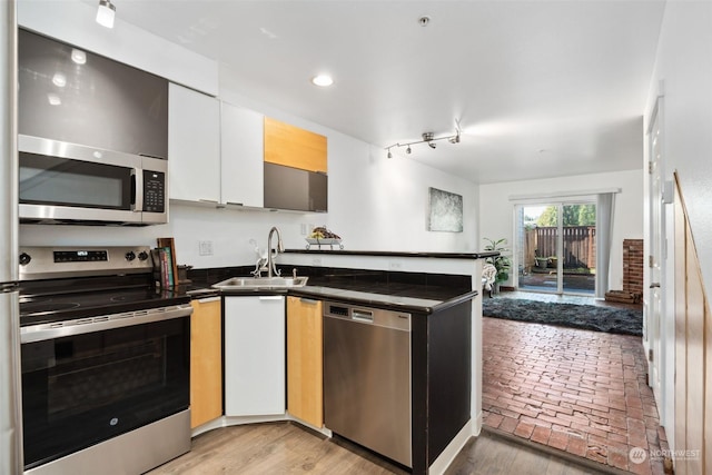 kitchen featuring sink, white cabinetry, stainless steel appliances, and track lighting