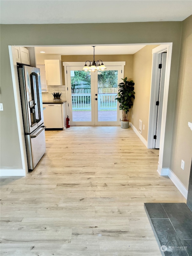 kitchen with stainless steel fridge, light hardwood / wood-style floors, and hanging light fixtures