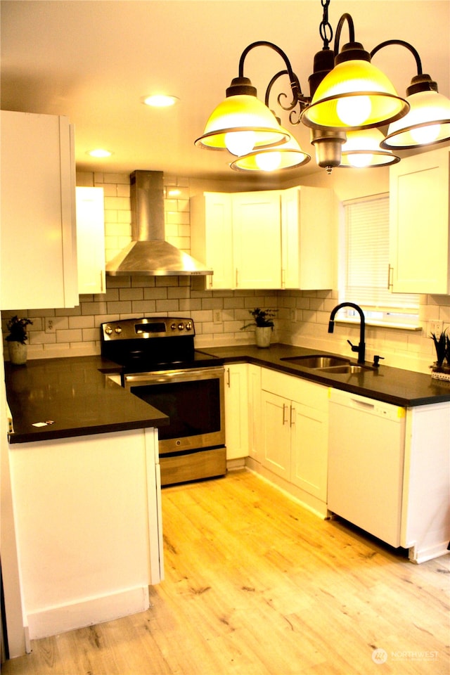 kitchen featuring white cabinetry, wall chimney range hood, white dishwasher, decorative light fixtures, and electric stove