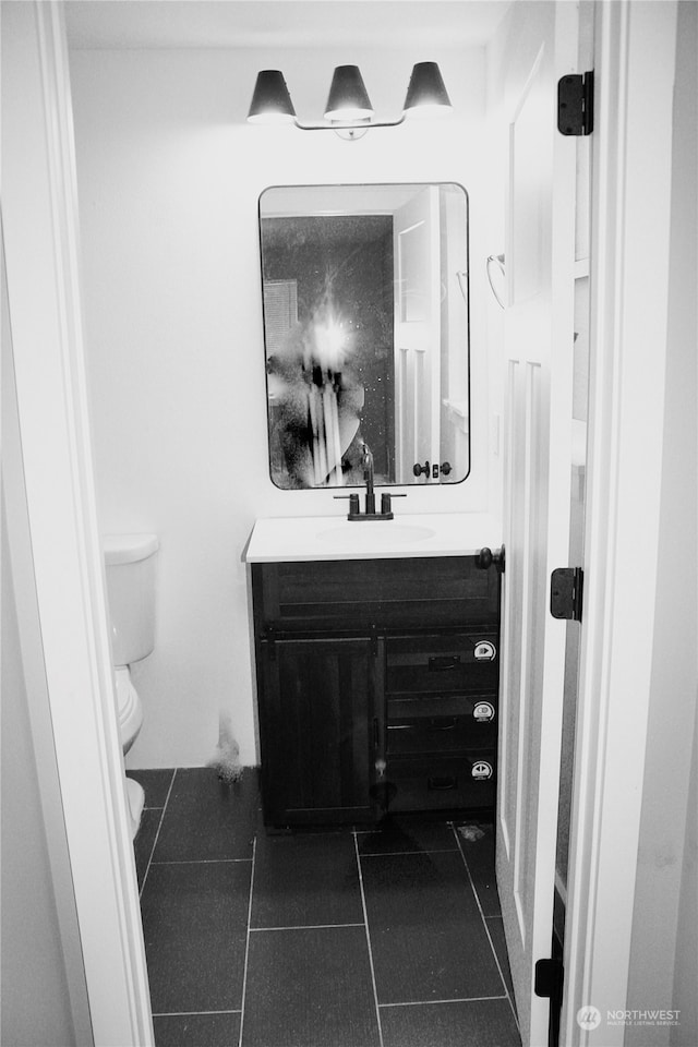 bathroom with toilet, vanity, and tile patterned floors