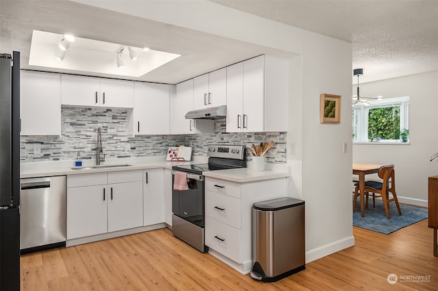 kitchen with pendant lighting, light wood-type flooring, sink, white cabinets, and stainless steel appliances