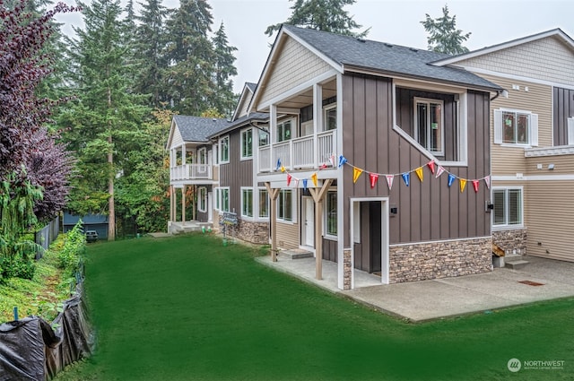 back of property with a patio, a balcony, and a lawn