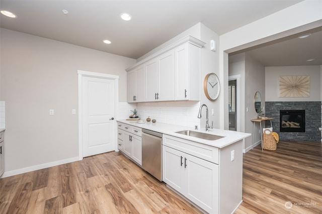 kitchen featuring dishwasher, sink, a fireplace, light hardwood / wood-style floors, and white cabinetry