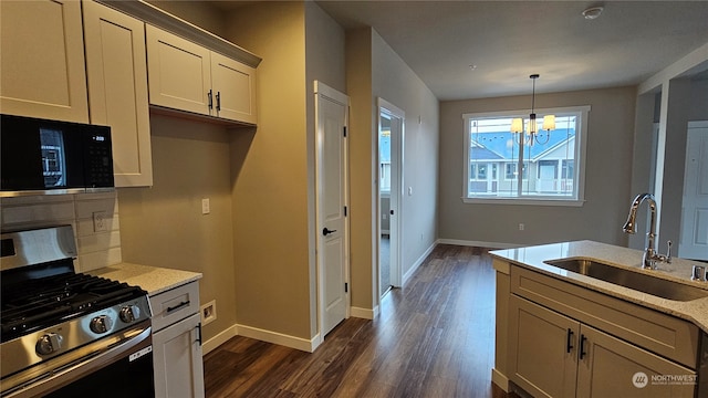 kitchen with stainless steel gas stove, sink, dark hardwood / wood-style flooring, pendant lighting, and a chandelier