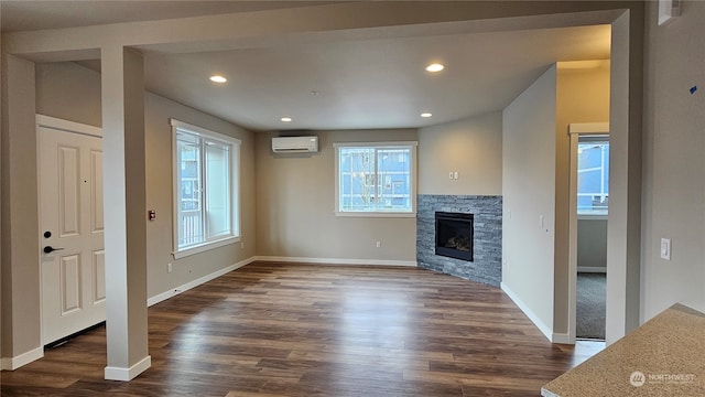 unfurnished living room with a fireplace, dark hardwood / wood-style floors, and a wall mounted air conditioner