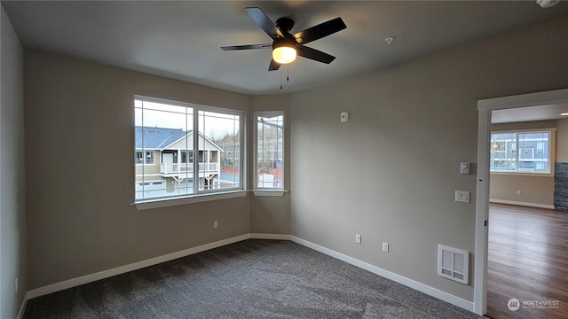 empty room with a wealth of natural light, hardwood / wood-style floors, and ceiling fan