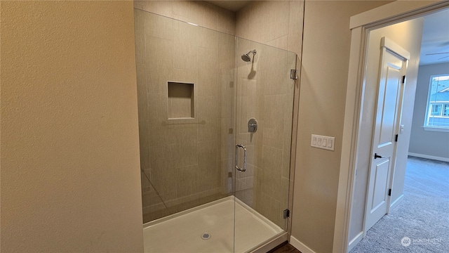 bathroom featuring ceiling fan and a shower with shower door