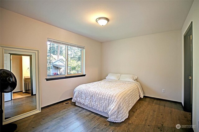 bedroom featuring ensuite bathroom and dark hardwood / wood-style flooring