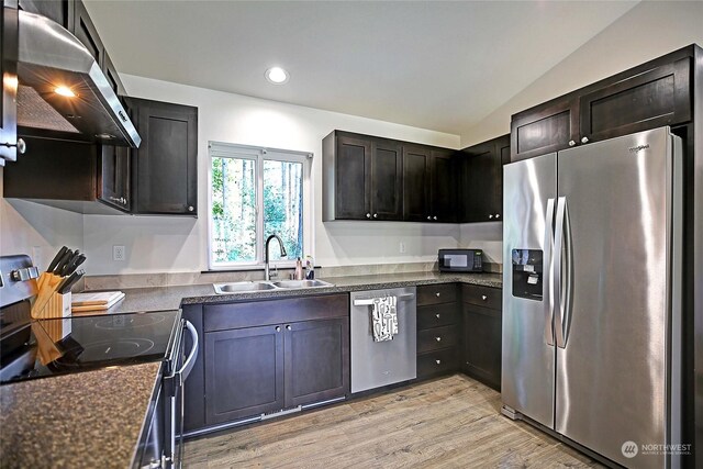 kitchen with lofted ceiling, sink, ventilation hood, appliances with stainless steel finishes, and light wood-type flooring