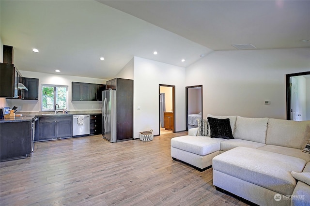 living room with lofted ceiling, light wood-type flooring, and sink