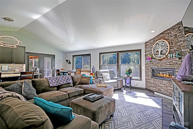 living room with a stone fireplace, vaulted ceiling, an inviting chandelier, and hardwood / wood-style flooring