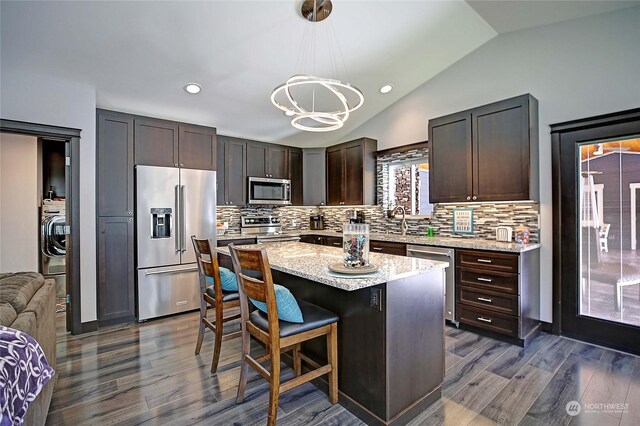 kitchen featuring pendant lighting, dark hardwood / wood-style floors, lofted ceiling, a kitchen island, and stainless steel appliances