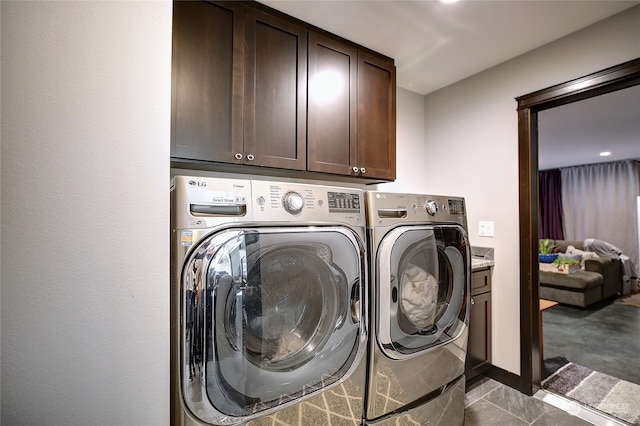 clothes washing area featuring cabinets and separate washer and dryer