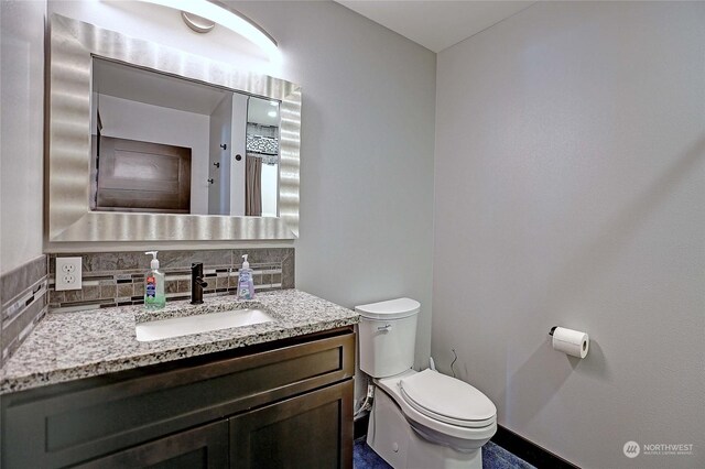 bathroom with vanity, toilet, and tasteful backsplash