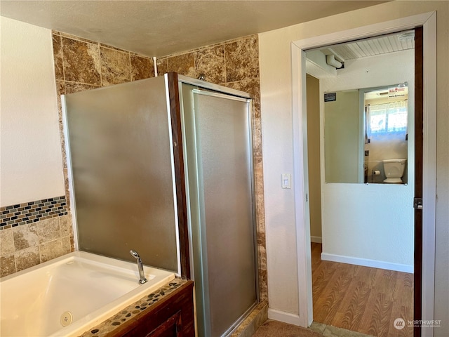 bathroom featuring a textured ceiling, independent shower and bath, and hardwood / wood-style floors