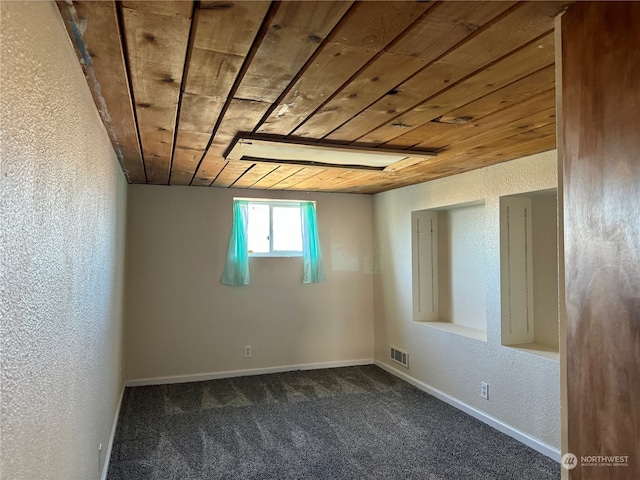 carpeted empty room featuring wood ceiling